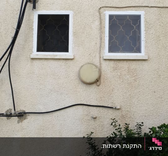 שני חלונות אלומיניום קטנים עם רשתות מותקנות בקיר חיצוני